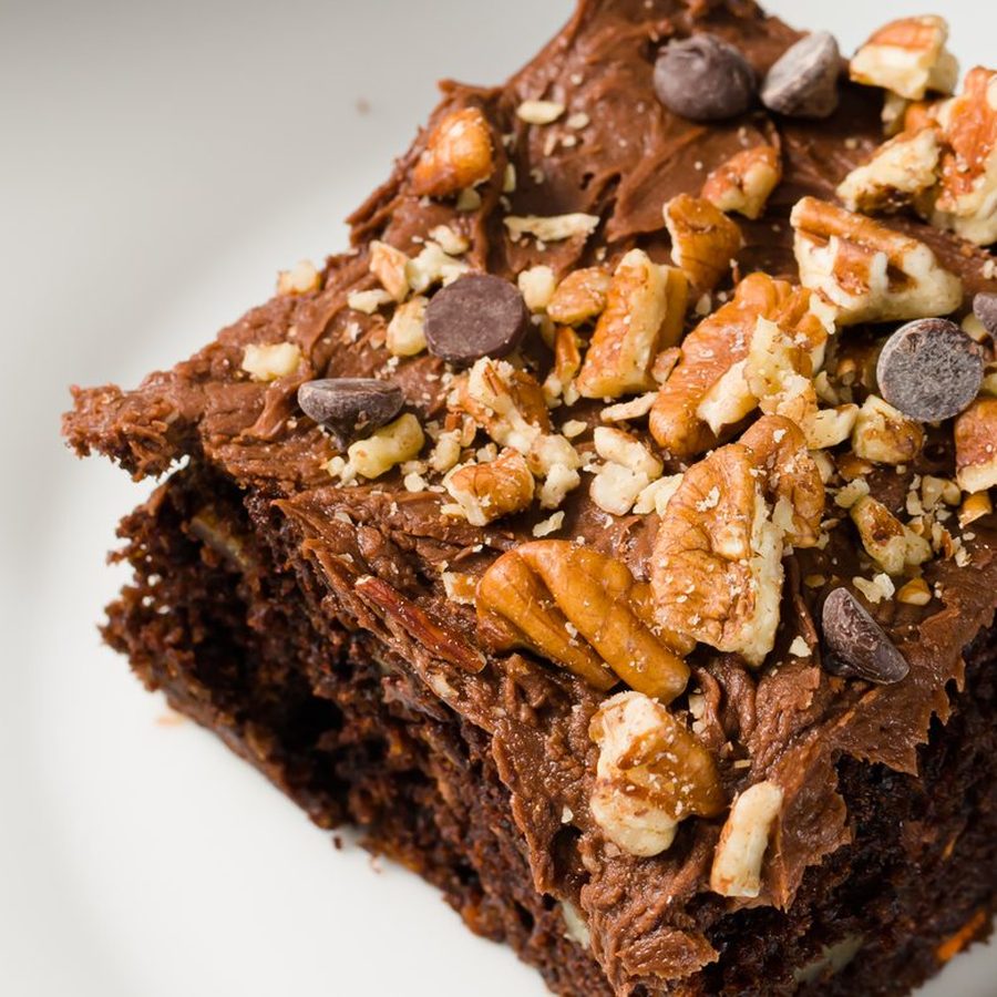 A square of chocolate carrot cake topped with frosting and pecans