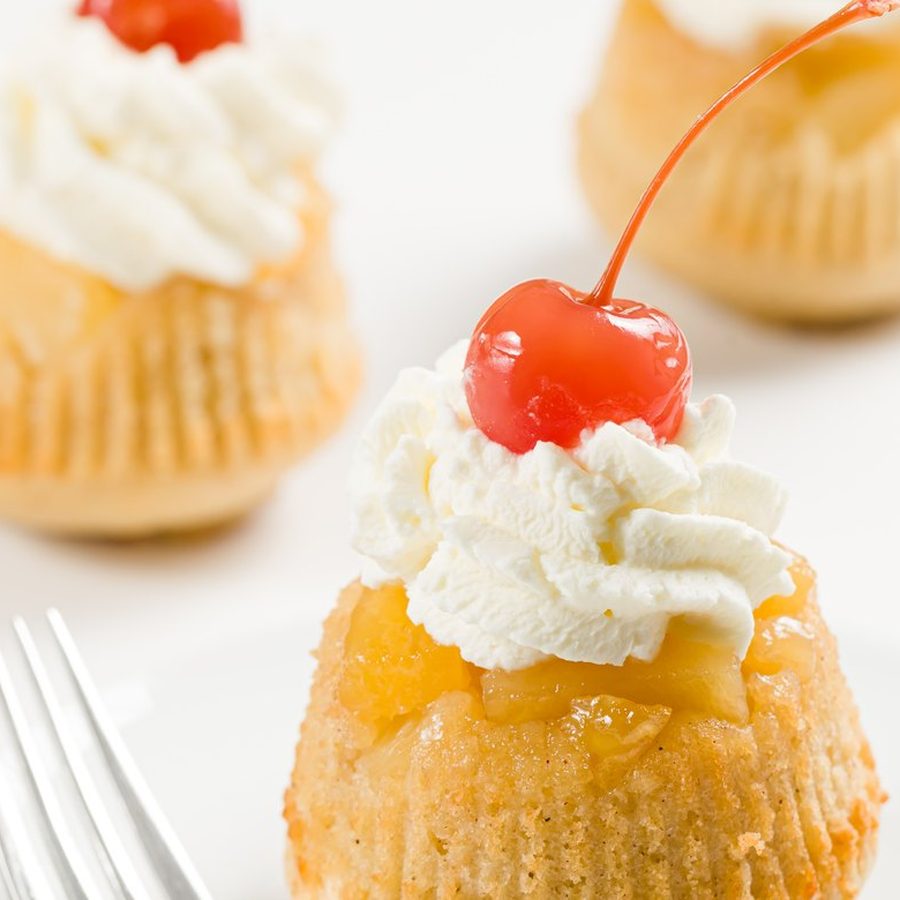 Pineapple upside-down cupcakes topped with whipped cream and cherries